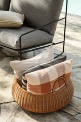 Braided Rattankorb mit Kissen auf einer Terrasse neben einem Loungesofa