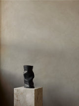 Schwarze Collapse Vase von Audo Copenhagen auf einem Steinsockel vor heller Wand