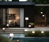 Mehrere Nordlux Kettle To-Go Leuchten auf einer Terrasse vor einem dunklen Gartenhaus