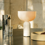 New Works Kizu Portable auf einem Metalltisch neben Vase und Schale im Abendlicht