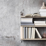 Detailansicht eines Regalbodens aus Eiche des String Pocket mit Büchern